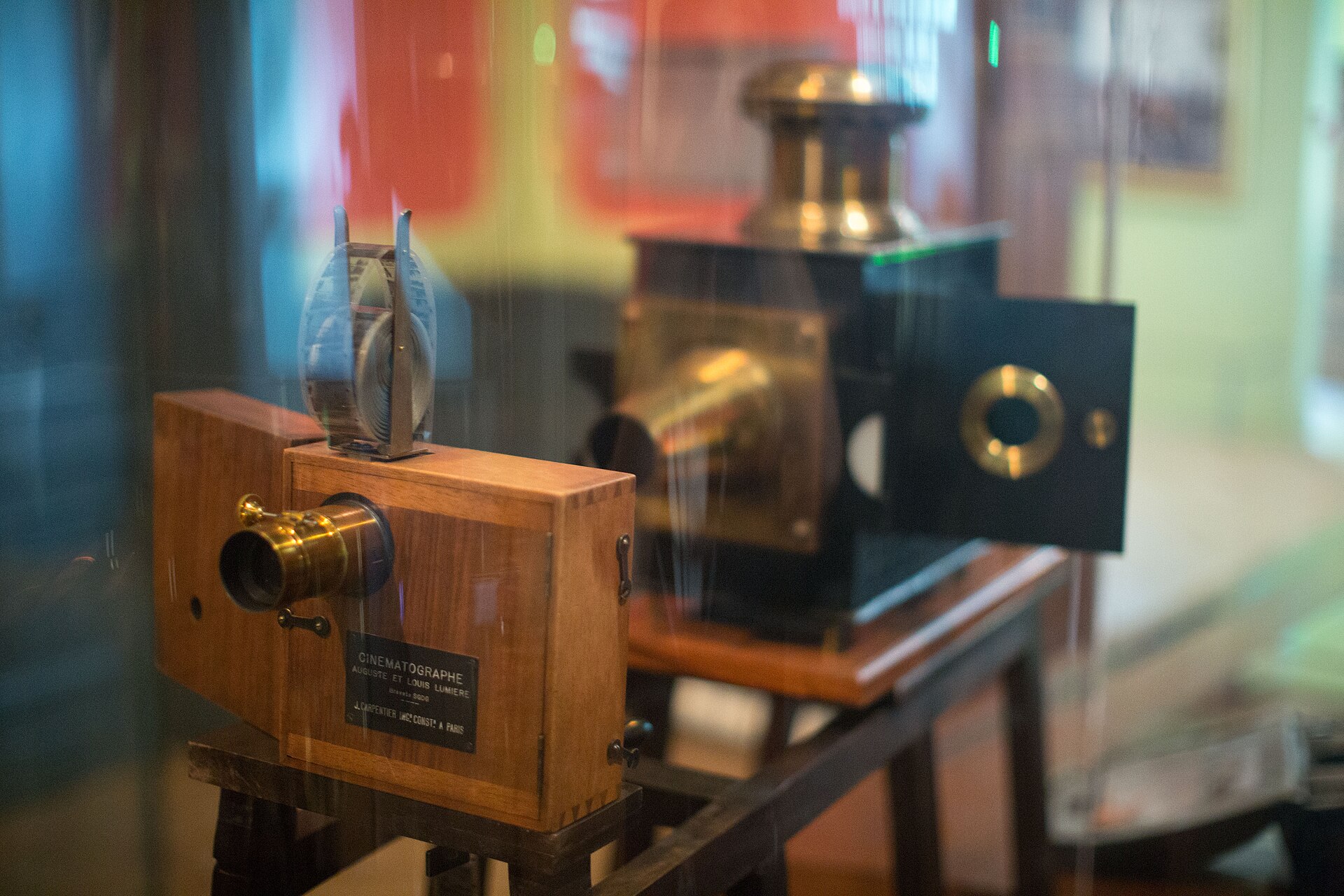 Cinématographe en bois des frères Lumière exposé en vitrine devant un ancien appareil de projection